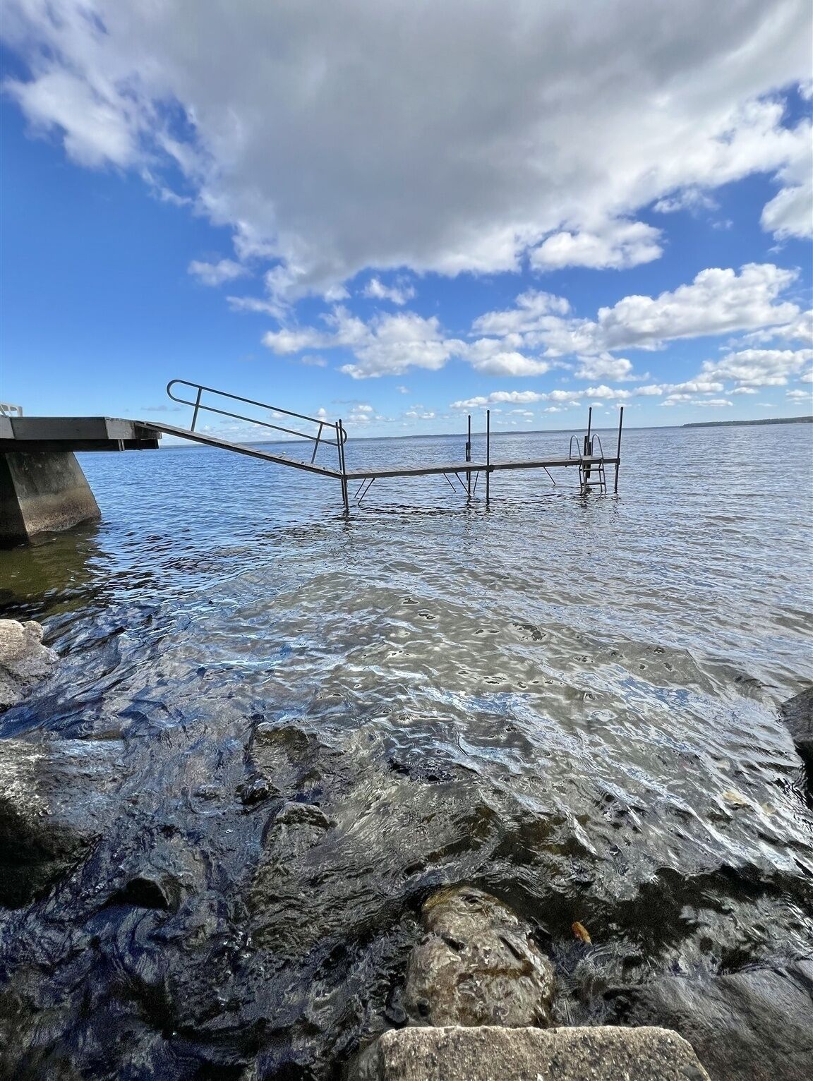 A pier extending into calm water with a clear sky above.