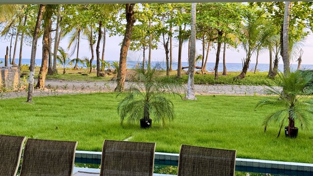 A poolside area with chairs and a view of the sea. - Esterillos Lote 6 Bedroom Home (Parrita)