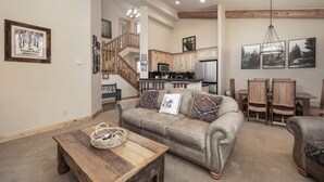 A spacious living room with a beige sofa, wooden coffee table, and a staircase leading to the upper floor. - Antler At Lakota 407 3 Bedroom Home (Winter Park)