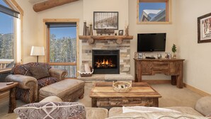 A cozy living room with a stone fireplace, a television, and comfortable seating. - Antler At Lakota 407 3 Bedroom Home (Winter Park)