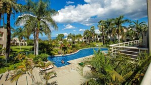 Ein Resort mit Swimmingpool, umgeben von Palmen und Blick auf den Ozean.
