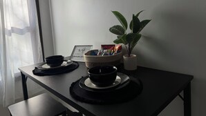 A dining table with black placemats, two black bowls, a woven basket with snacks, and a potted plant. - 1bd apt, 2 min walk to Albany med, off street parking and washer/dryer (Albany)
