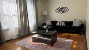 A living room with a black sofa, a coffee table, and a patterned rug. - 1bd apt, 2 min walk to Albany med, off street parking and washer/dryer (Albany)