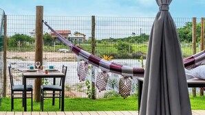 A room with a bed, a hammock, a table with chairs, and a view of the outdoors.