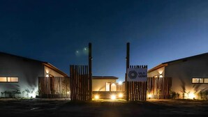 A modern building with a gated entrance, illuminated by exterior lights, and a sign reading "VILA GEMMA".