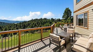 A deck with outdoor furniture, a wooden railing, and a view of a forested area. - Quinn Creek Chalet-Great home to relax with family & enjoy the views! (Bozeman)