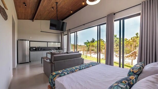 A modern bedroom with a large bed, a sofa, and a kitchen area with a TV.