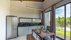 A modern kitchen with a built-in refrigerator, a dining table set for four, and a large window offering a view of the outdoors.