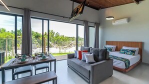 Una habitación moderna con una cama grande, un sofá y un comedor con una mesa dispuesta para dos.