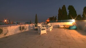 Une terrasse extérieure avec des sièges et une vue sur la ville au crépuscule.