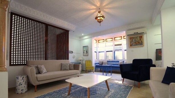 Un salon avec un canapé, une table basse et un tapis bleu à motifs.