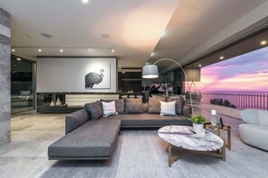 A modern living room with a sectional sofa, a round coffee table, and a large window overlooking a sunset. - One Eighty Marino (Marino)
