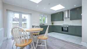 Una cocina moderna con comedor, que cuenta con tragaluces, armarios verdes y piso de mármol.