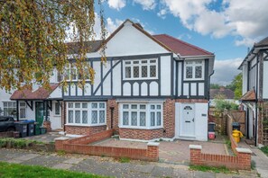 A two-story Tudor-style house with a steeply pitched roof, dormer windows, and a brick facade. - A wonderful and spacious house in a charming road (Greater London)