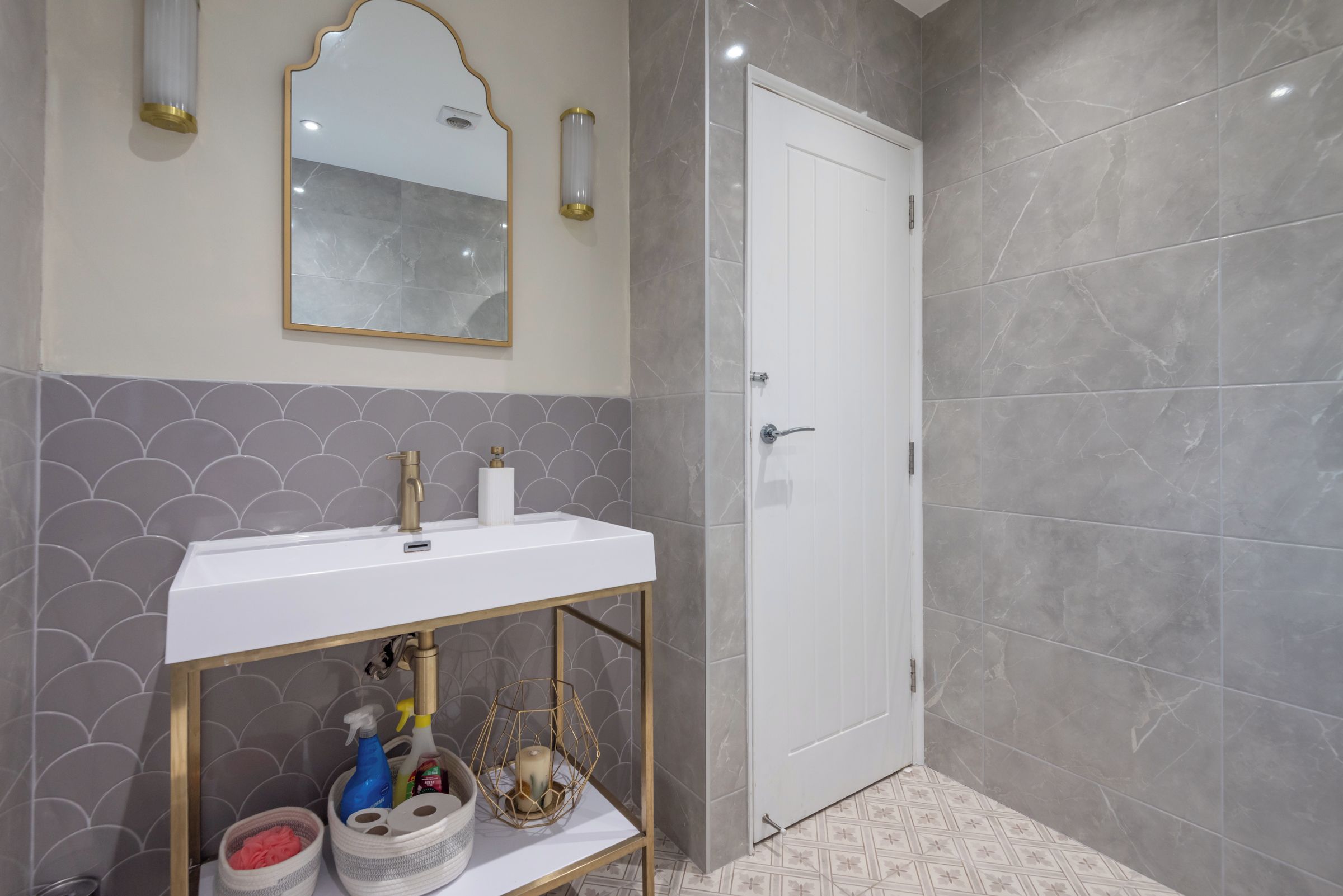 A bathroom with a white sink, a mirror with a gold frame, and a door.