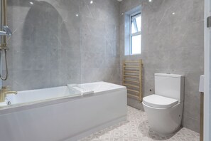 A modern bathroom with a freestanding bathtub, a toilet, and a towel rack. - A wonderful and spacious house in a charming road (Greater London)