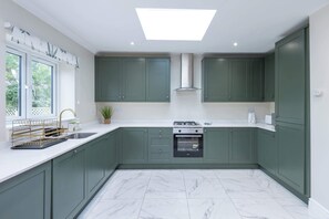 Una cocina moderna con gabinetes verdes, una estufa a gas y un horno empotrado.