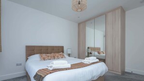 Un dormitorio con una cama grande, un armario, un espejo y una lámpara colgante.