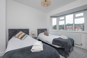 A hotel room with two beds, a window, and a view of buildings outside. - A wonderful and spacious house in a charming road (Greater London)