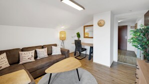 Una sala de estar moderna con un sofá marrón, una mesa de centro de madera y una zona de comedor con una mesa y sillas de madera.