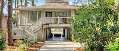 A two-story house with a covered front porch, a staircase, and a driveway leading to a garage.