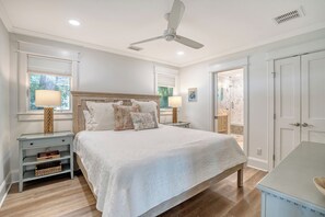A bedroom with a bed, nightstands, a ceiling fan, and a bathroom door.