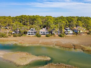 A coastal property with multiple houses surrounded by dense trees and a marshy area.