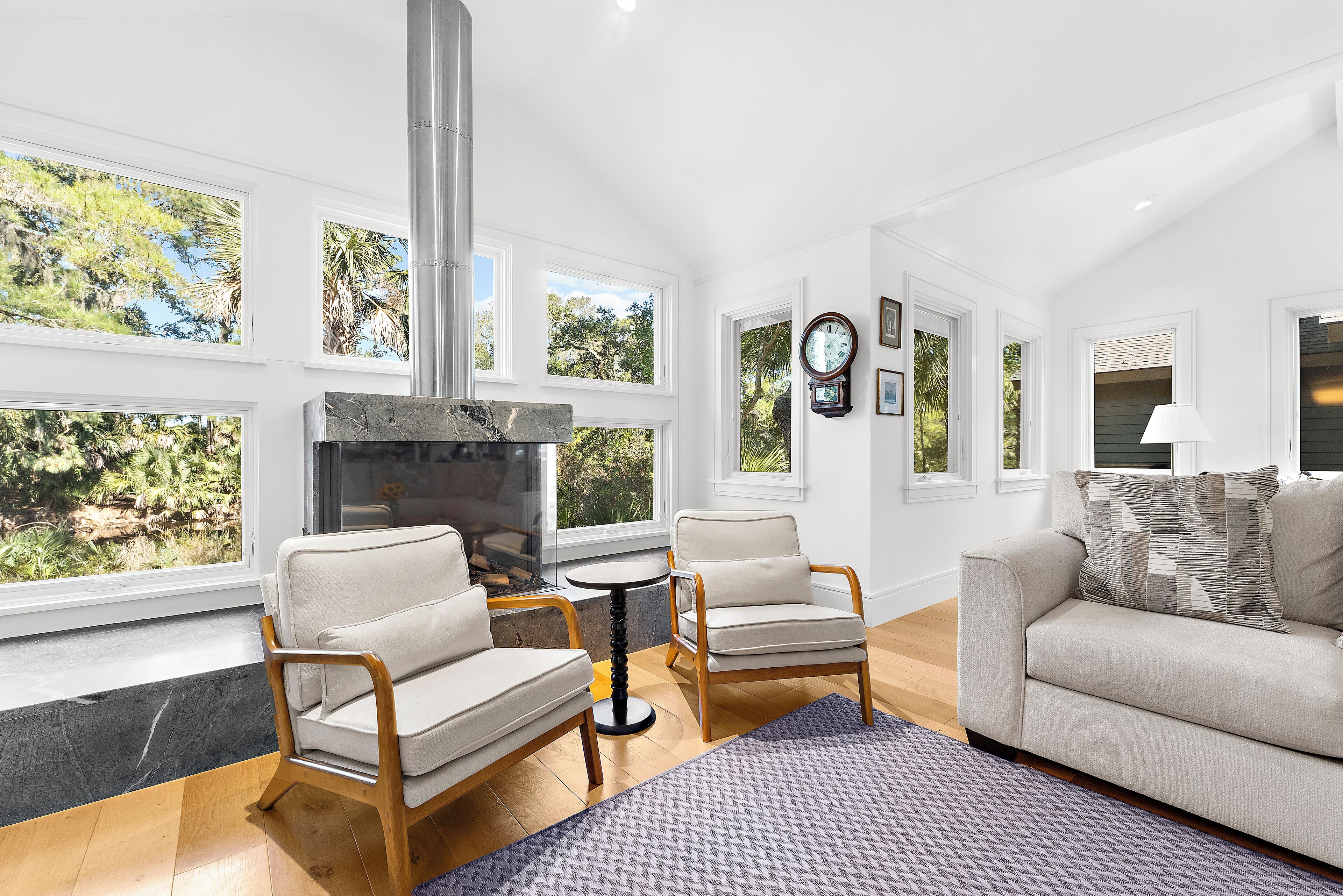 A modern living room with a fireplace, large windows, and a cozy seating area.