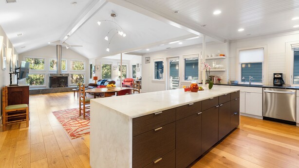 A spacious kitchen with a large island, wooden flooring, and a view of the outdoors through large windows. - Yards to the beach, stunning new reno (Kiawah Island)