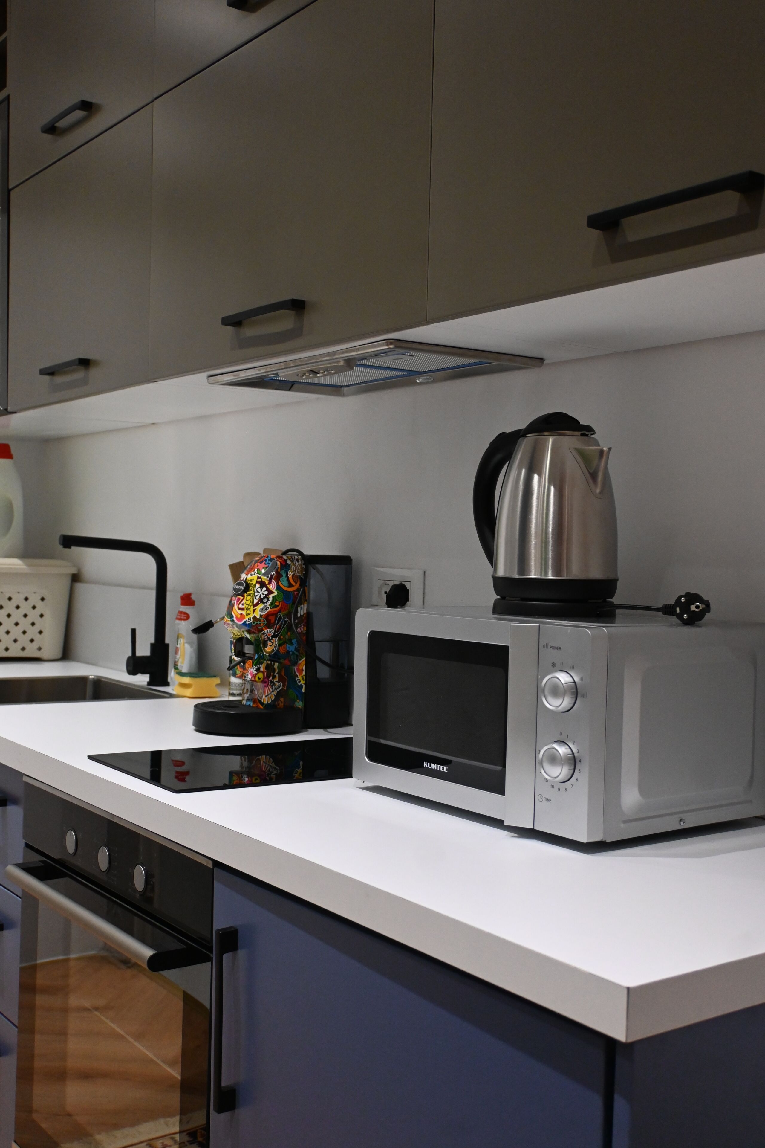 A kitchen with a microwave, kettle, and a colorful bag on the counter.