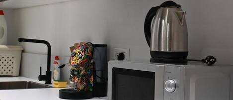 A kitchen with a microwave, kettle, and a colorful bag on the counter.