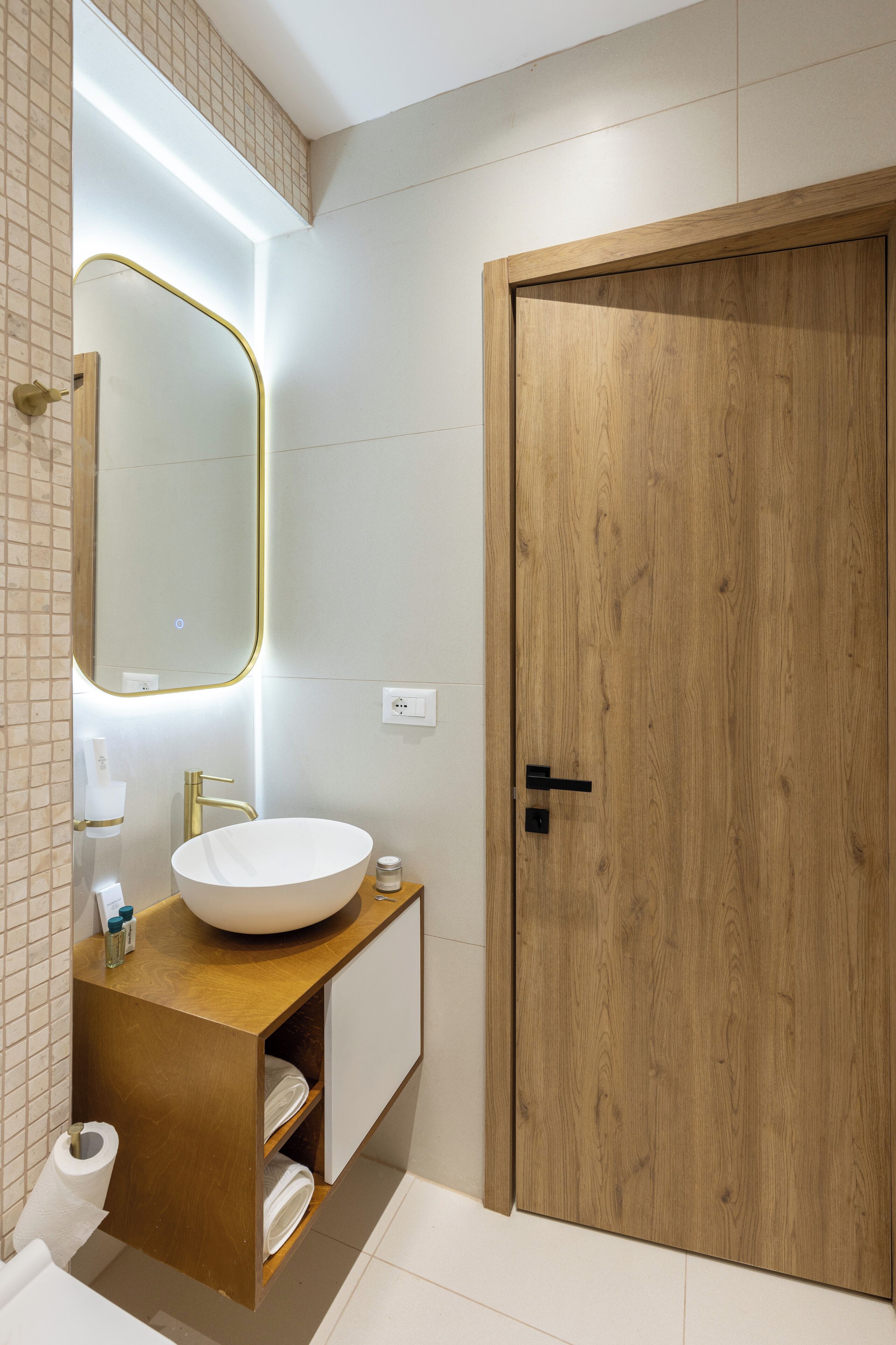 Un baño moderno con tocador de madera, un espejo grande y una puerta de madera.
