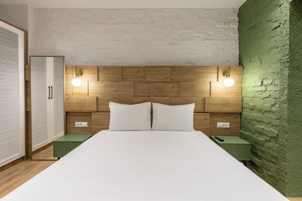 A bedroom with a wooden headboard, two bedside tables, and a green nightstand. - Vatër Apartments (Tirana)