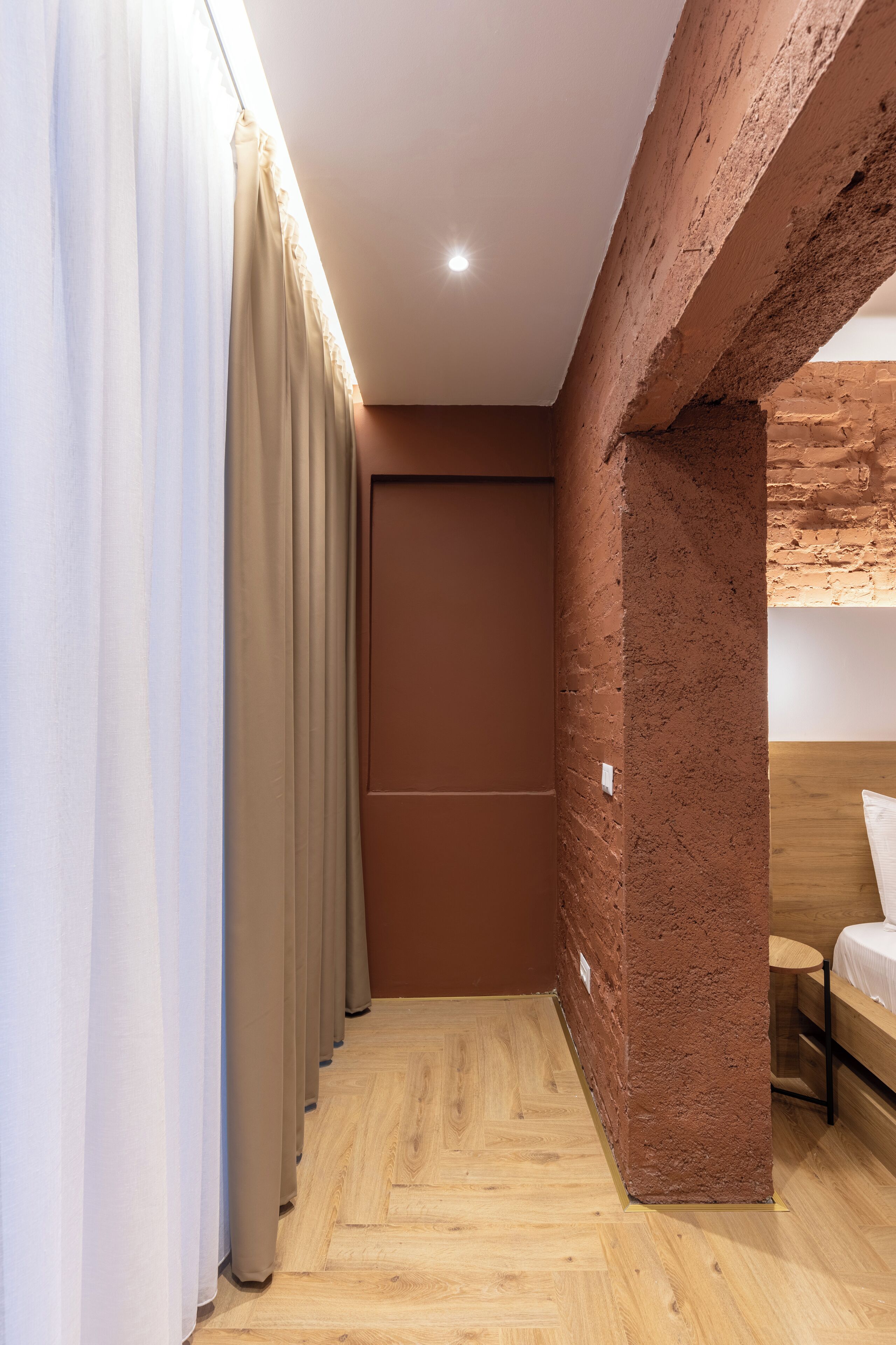 Un couloir étroit avec un plancher en bois, un mur en briques et une porte.