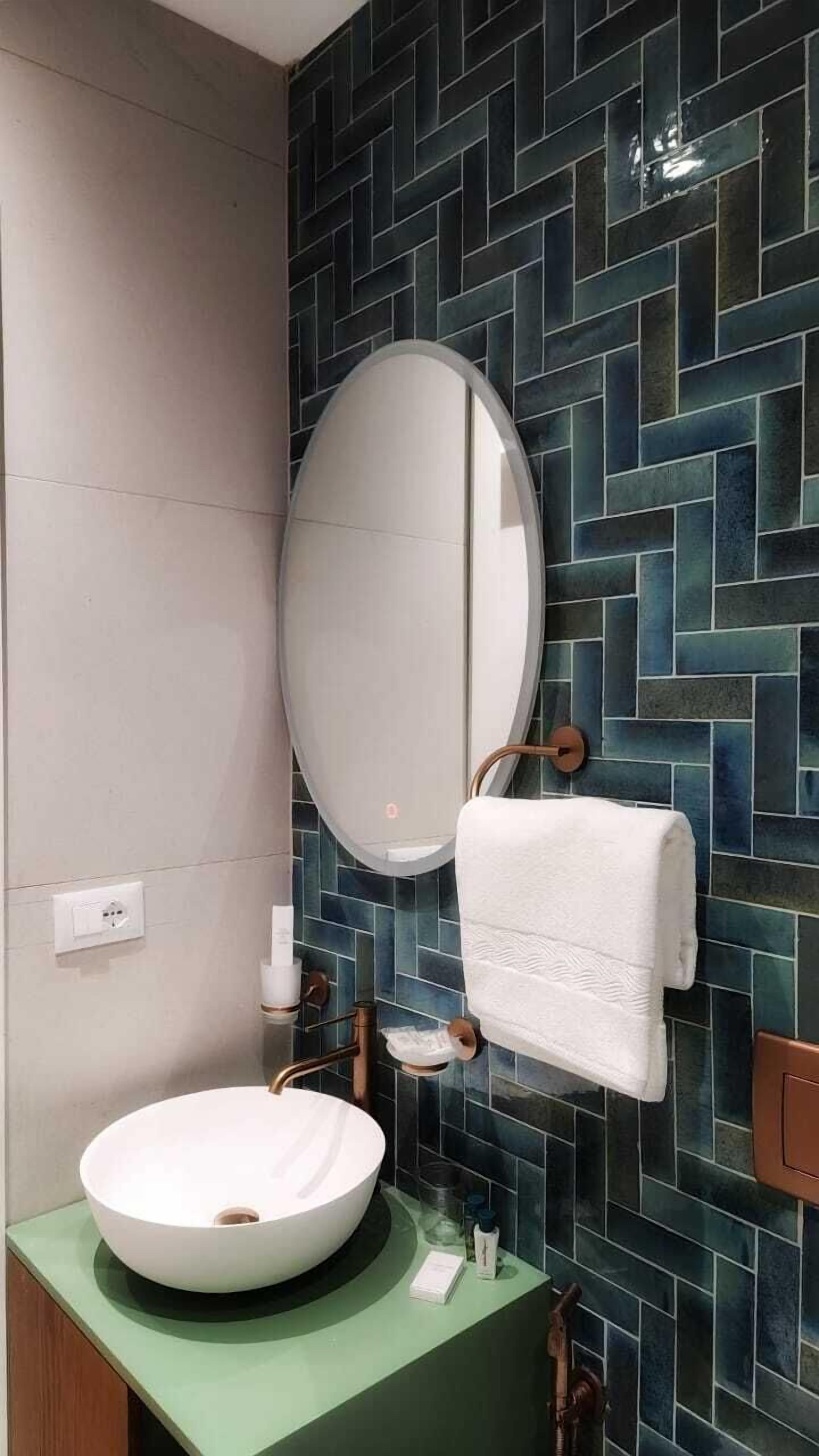 Un bagno con un lavabo rotondo, uno specchio e un portasciugamani.