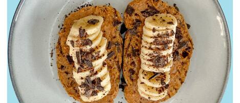 Un plato con dos porciones de comida coronadas con rodajas de plátano y virutas de chocolate.