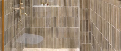 A modern shower with a handheld showerhead and a wall-mounted faucet.