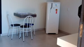 Une petite cuisine équipée d’un réfrigérateur, une table avec deux chaises et un tapis à carreaux rouges sur le sol.