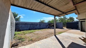 Un espace extérieur doté d’un mur en béton, d’un patio couvert et d’un petit abri de jardin.