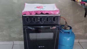 Un poêle noir doté d’un panneau de commande, d’une bouteille de gaz et d’un sol carrelé.