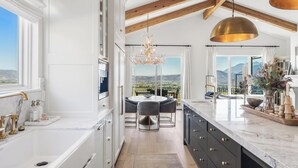 Una cocina moderna con una isla grande, un comedor con vistas y una araña.