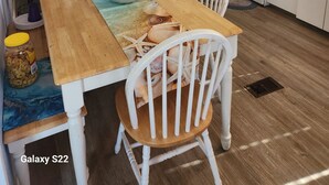 Une cuisine de taille réduite avec des meubles blancs, une table à manger en bois et un four à micro-ondes.