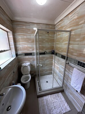 Bañera con ducha, toallas, jabón, shampoo