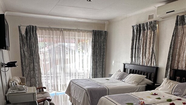 A hotel room with two beds, a desk, and a window with curtains. - Mosele wa Pula Guesthouse  (Rustenburg)