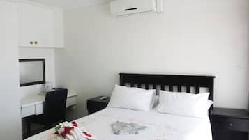 Une chambre d’hôtel équipée d’un lit, d’un bureau, d’une chaise, d’une table de chevet et d’un climatiseur fixé au mur.