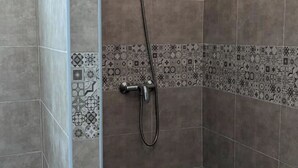 Een douchegedeelte met een betegelde rand en een handdouche.