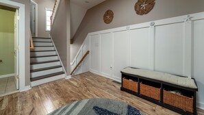 A staircase leading to a landing with a bench and baskets, a wooden floor, and decorative wall clocks. - 4 BR, 4.5 BA Townhouse- Park & Walk to shops, eateries & beach in Rehoboth. (Rehoboth Beach)