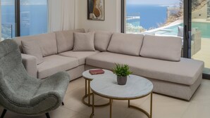A modern living room with a beige sectional sofa, a grey armchair, and a small round table with a plant. - Luxury Villa Vie (Malevizi)