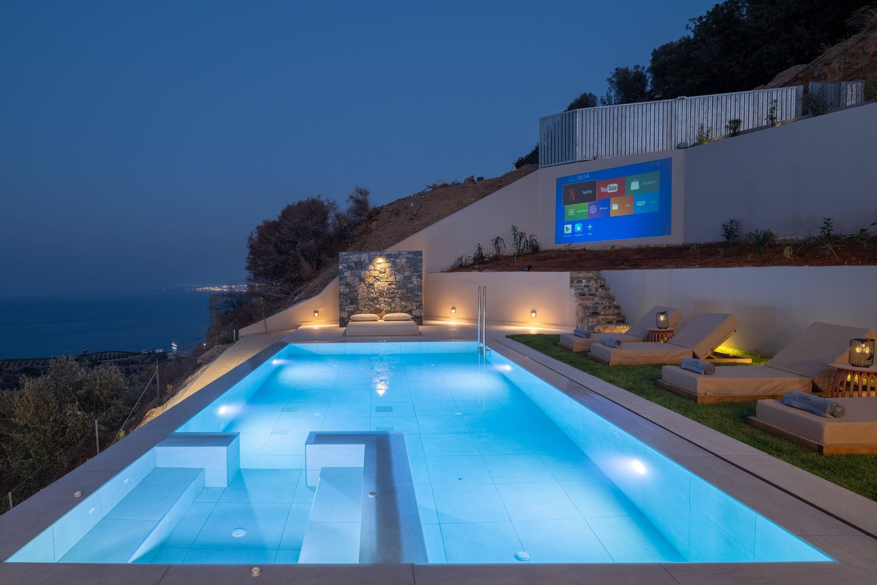 Ein Swimmingpool mit Blick auf den Ozean, eine Steinmauer und ein Bildschirm mit Symbolen.