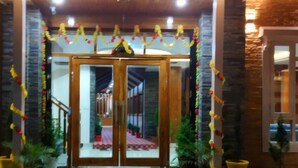 A hotel entrance with a wooden facade, double doors, and a green carpet leading up to the steps. - Hotel Apple View Narkanda (Theog)